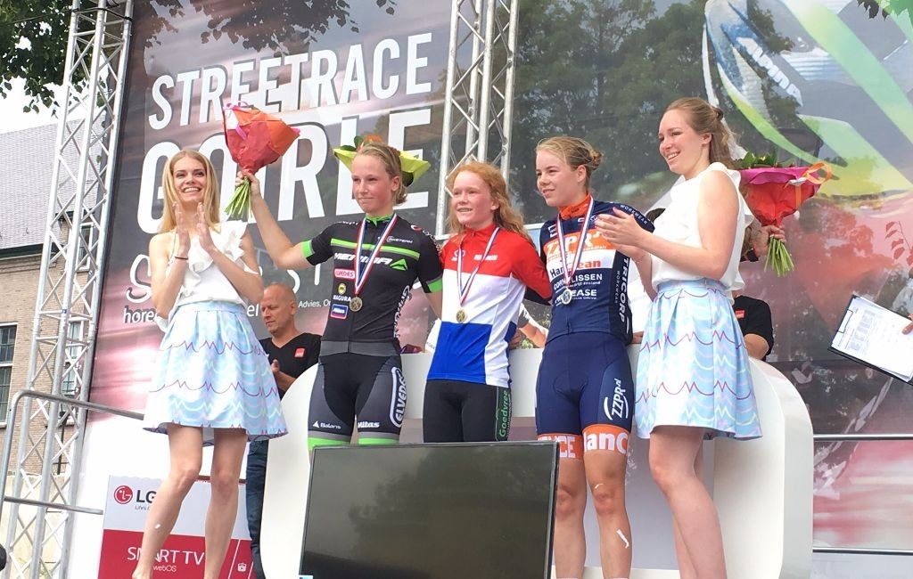 Drie wielrensters met medailles op het podium van het NK Streetrace in Goirle, met bloemen en hostesses