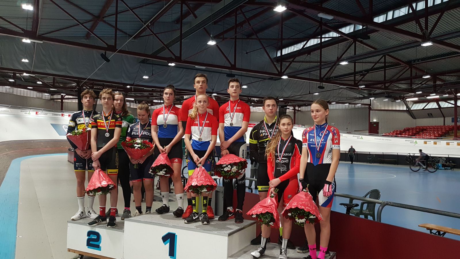 Jeugdrenners en nieuwelingen met bloemen en medailles op het podium in de wielerbaan na het NK Omnium Sprint