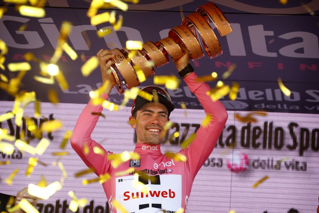 Tom Dumoulin in de roze trui heft de Giro-trofee omhoog op het podium in Milaan, tussen dwarrelende gouden confetti