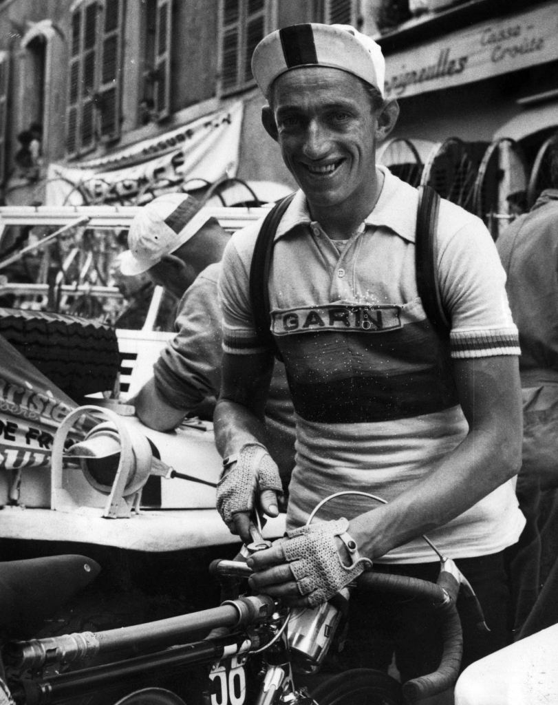 Wout Wagtmans lacht met koerspet en mitaines achter zijn racefiets na een rit